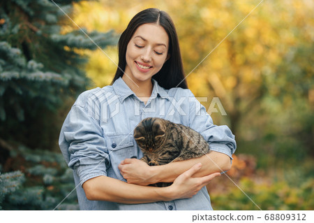 Girl in a blue shirt standing on trees background 68809312