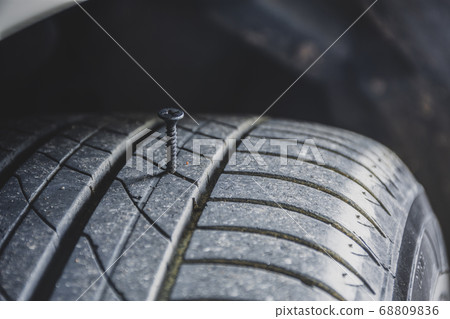 Metal screw puncturing into a car tire Metal screw puncturing into a car tire 68809836