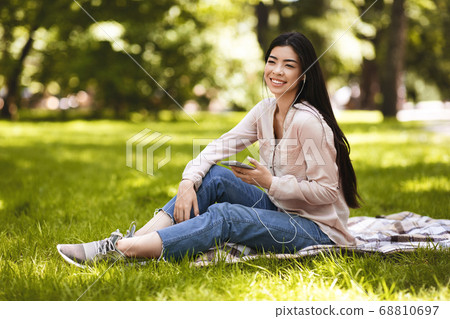 Happy Girl Listening Audio Book Outdoors With App On Smartphone And Earphones Happy Girl Listening Audio Book Outdoors With App On Smartphone And Earphones 68810697