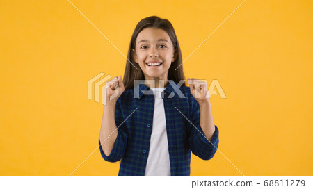 Little girl celebrating over yellow studio background 68811279