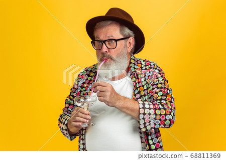 Senior hipster man wearing eyeglasses posing on yellow background. Tech and joyful elderly lifestyle concept Senior hipster man wearing eyeglasses posing on yellow background. Tech and joyful elderly lifestyle concept 68811369