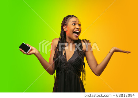 Portrait of young woman in neon light on gradient backgound. The human emotions, black friday, cyber monday, purchases, sales, finance concept. Portrait of young woman in neon light on gradient backgound. The human emotions, black friday, cyber monday, purchases, sales, finance concept. 68812094