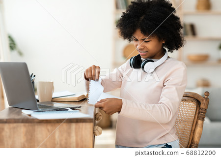 Teenager Girl Tearing Page Out Of Work Book Sitting Indoors Teenager Girl Tearing Page Out Of Work Book Sitting Indoors 68812200