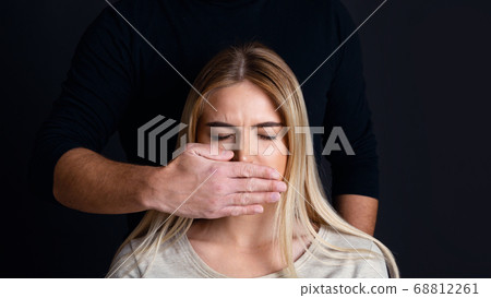 Psychological and physical pressure man on woman. Male hand closes mouth of woman Psychological and physical pressure man on woman. Male hand closes mouth of woman 68812261