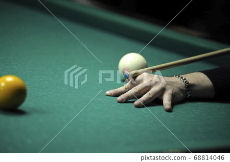 Playing billiard. Player arm gets ready to stroke a ball with a cue 68814046