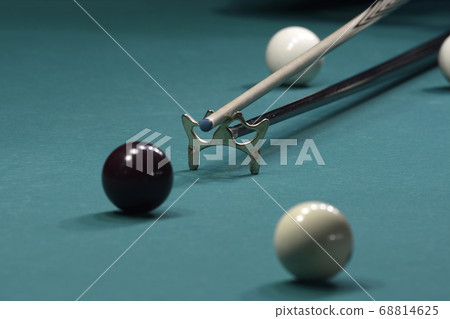Billiard player striking a ball with cue stick 68814625