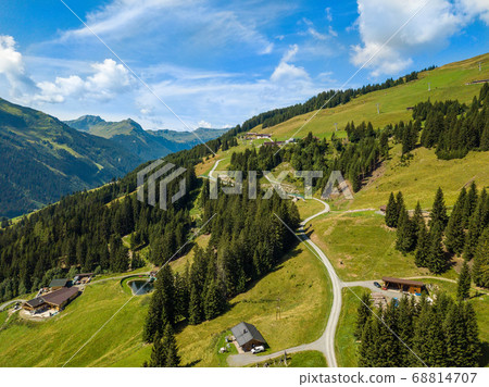 Aerial view on cozy hut and mountain in the skiing region of Hinterglemm in the Alps in Austria on a sunny summer day Aerial view on cozy hut and mountain in the skiing region of Hinterglemm in the Alps in Austria on a sunny summer day 68814707