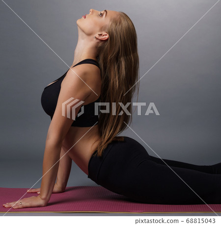 Pretty blonde fitness trainer exercising in studio Pretty blonde fitness trainer exercising in studio 68815043