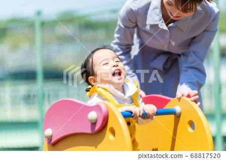 Cute little girl playing with playground equipment with mom 68817520