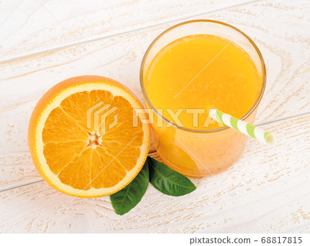 Glass of freshly squeezed orange juice and half of ripe sweet orange on a white wooden table.  68817815