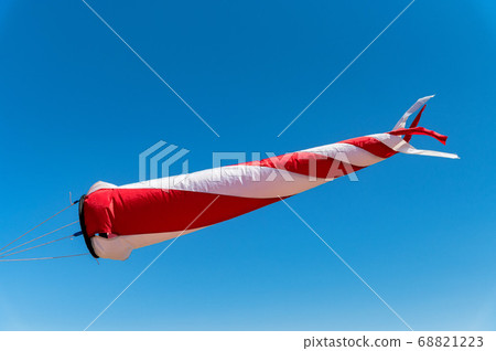 Red and white windsock on a background of blue sky Red and white windsock on a background of blue sky 68821223