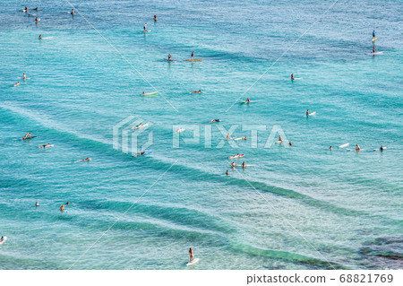 Aerial view of beach travel vacation Hawaii holiday with surfers people swimming in blue ocean water surfing on waves with surfboards, sup paddle boards. Watersport activity summer sport lifestyle. Aerial view of beach travel vacation Hawaii holiday with surfers people swimming in blue ocean water surfing on waves with surfboards, sup paddle boards. Watersport activity summer sport lifestyle. 68821769