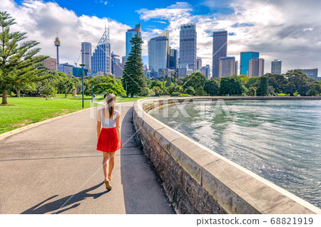 Sydney city girl tourist walking in urban park with skyscrapers skyline in the background. Australia travel vacation in the summer. Australian people lifestyle living. 68821919