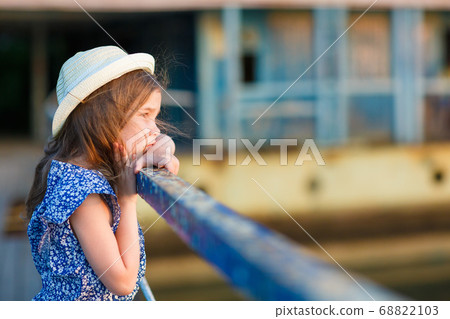 little girl standing on porch of old ruined house. 68822103
