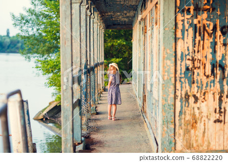 little girl standing on porch of old ruined house. 68822220