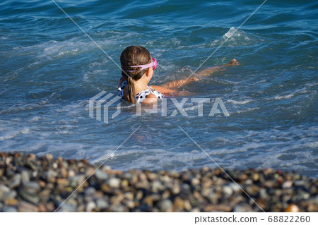 Little girl swims in the waves on the coast 68822260