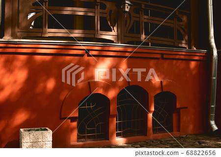 Facade of the historic building yellow-orange building with window arches. 68822656