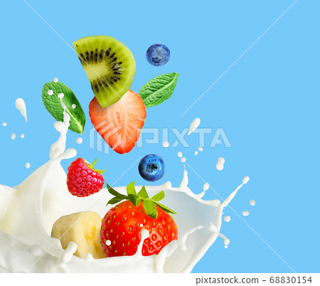 Fruit and berry falling in milk and splashing isolated on blue background. Smoothie or milkshake prepearing. 68830154