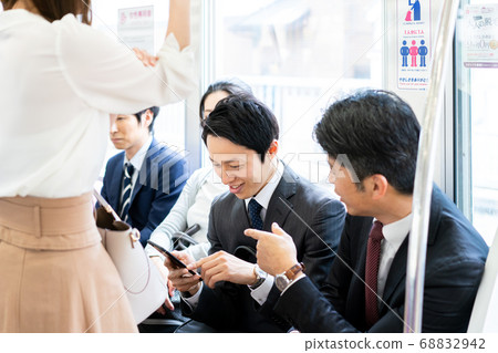 Businessmen watching smartphones on the train "Keio Electric Railway Co., Ltd." 68832942