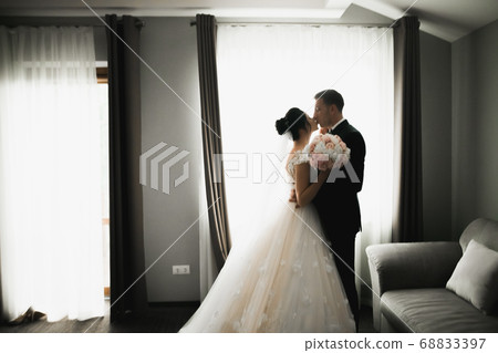 Beautiful bride and groom embracing and kissing on their wedding day Beautiful bride and groom embracing and kissing on their wedding day 68833397