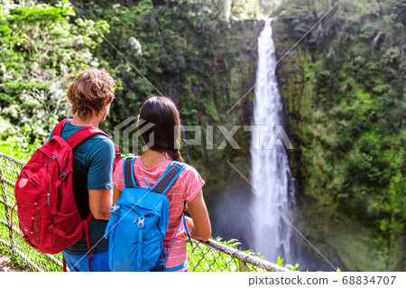 Hawaii Akaka Falls tourists at hawaiian waterfall. Young couple backpackers watching water fall on Hawaii, Big Island, USA. Travel tourism people concept. 68834707
