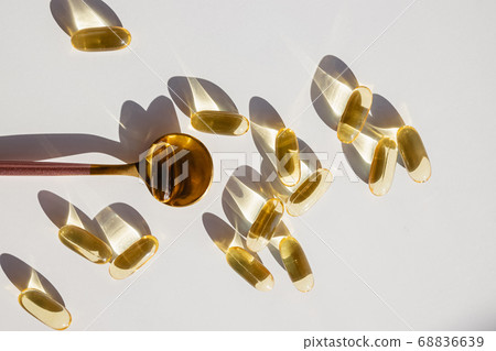 Omega 3 capsules on white table in natural sunlight 68836639