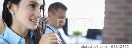 Young woman is talking on microphone in an office. Young woman is talking on microphone in an office. 68842425