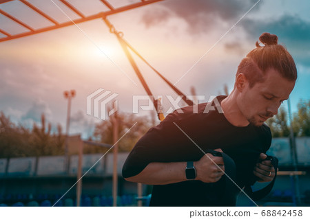 yound sporty athlete or bodybuilder has fitness workout with trx outdoor 68842458