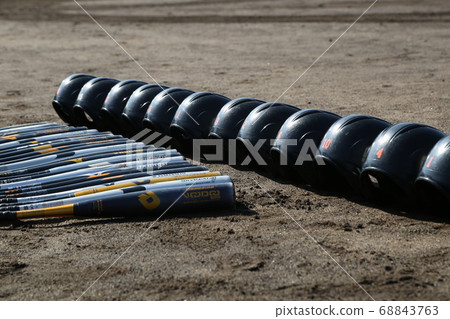 Bat and helmet lined up on the ground 68843763
