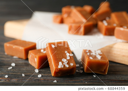 Salted caramel candies on wooden background, close 68844359
