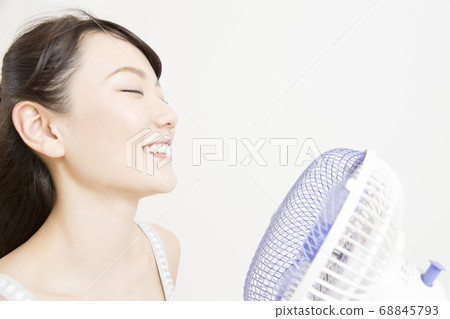 A woman in the wind of an electric fan 68845793