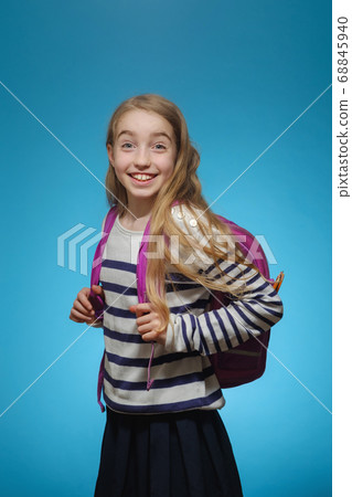 Little Caucasian girl with a school backpack on a blue background Little Caucasian girl with a school backpack on a blue background 68845940