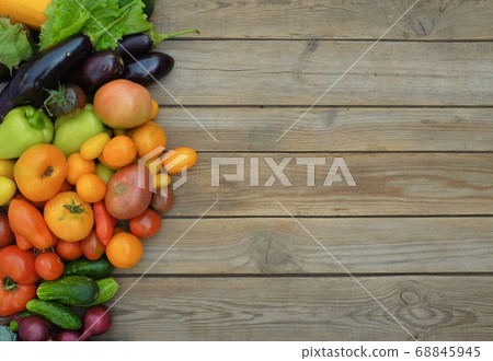 Many different colorful vegetables lie on a wooden board on the left 68845945