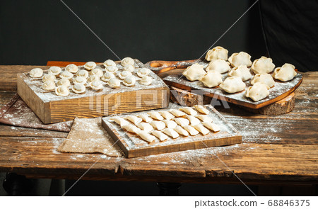 Variety of semi-finished dumplings on wooden board Variety of semi-finished dumplings on wooden board 68846375