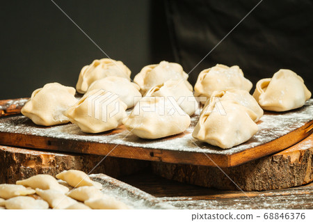 Semi-finished dumplings manti on the wooden board 68846376