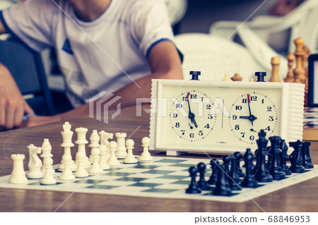 Chess board with chess pieces and clock on wooden Chess board with chess pieces and clock on wooden 68846953