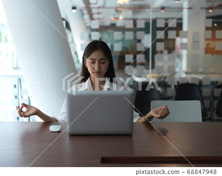 Portrait of female office worker meditating in Portrait of female office worker meditating in 68847948