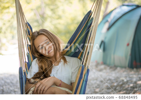 A young woman relaxing in a hammock in a wood. A young woman relaxing in a hammock in a wood. 68848495