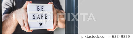 Man holding lightbox with text Be safe in his hand 68849829