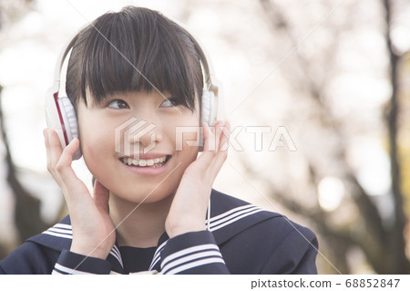 Female junior high school student listening to music with headphones 68852847