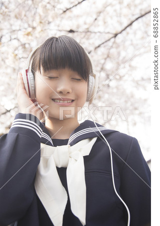 Female junior high school student listening to music with headphones 68852865