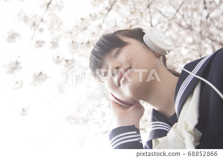 Female junior high school student listening to music with headphones 68852866