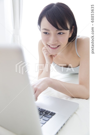 Woman looking at laptop in bed Woman looking at laptop in bed 68853635