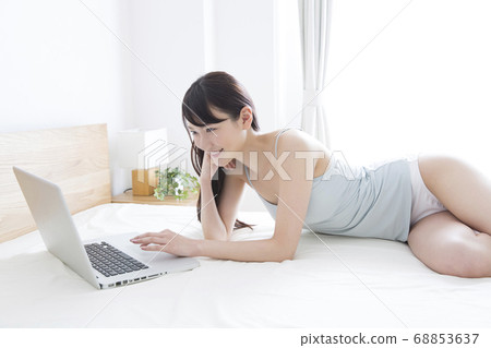 女人在床上看著筆記本電腦 68853637