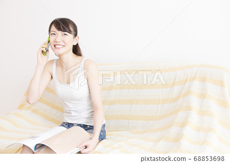 A woman calling while looking at a magazine 68853698