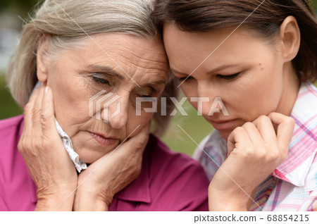 Close up portrait of sad senior woman with adult daughter Close up portrait of sad senior woman with adult daughter 68854215