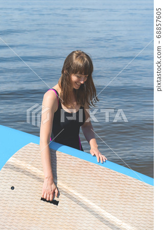A beautiful woman is engaged in summer active sports on the river on a SUP board 68857605