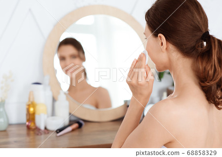 Young woman applying face toner on her face Young woman applying face toner on her face 68858329