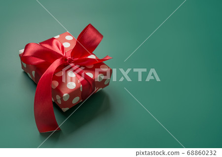 Holiday gift in red and white packaging with polka dots and red bow on green. Xmas present. Holiday gift in red and white packaging with polka dots and red bow on green. Xmas present. 68860232