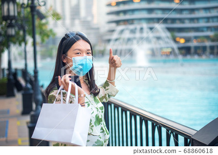 Happy female Asian tourist wearing face mask at 68860618